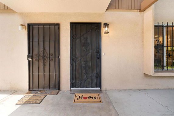 Front view of a house entrance with two doors and welcome mats.