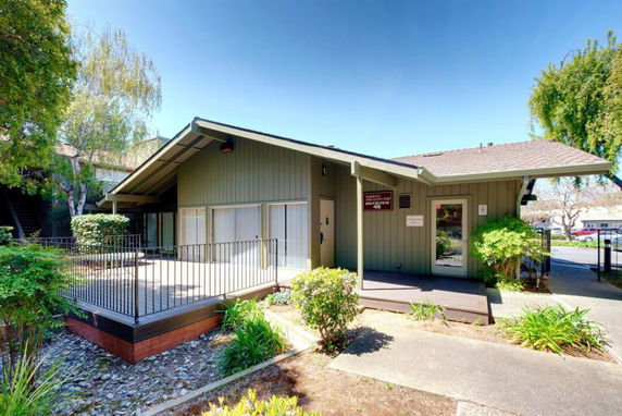 Front view of a single-story building with a small patio and railing.