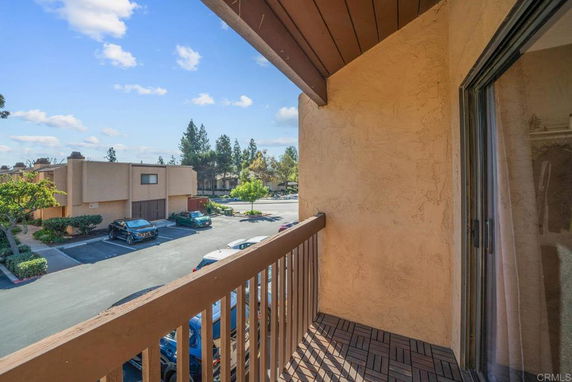View from a balcony overlooking a parking area and residential buildings.
