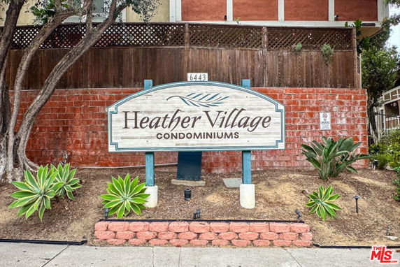 Sign for Heather Village Condominiums in front of brick and wood structure.