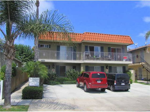 Front view of a two-story building with a balcony and parking area.