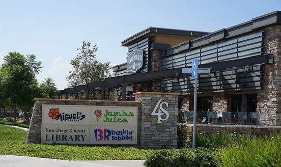 Front view of a commercial building with various store signs and stone facade.