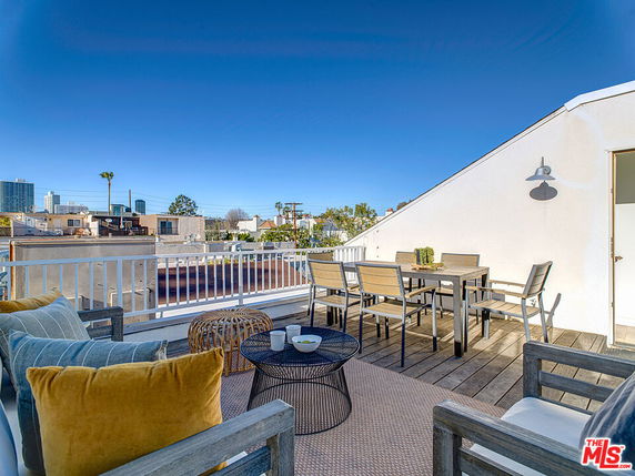 Rooftop patio with seating and dining area, offering a view of surrounding buildings and cityscape.