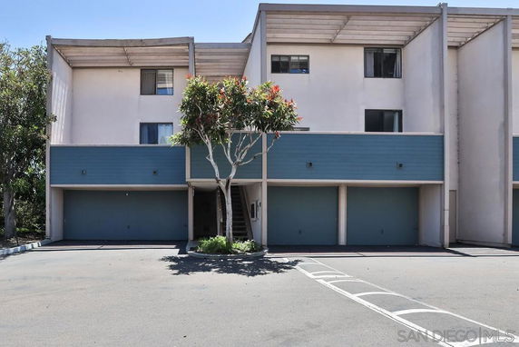 Front view of a three-story residential building with a garage on the ground floor and blue paneling.