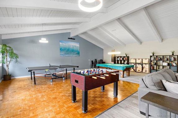 Indoor recreation area with games like table tennis and foosball, along with seating and shelves.