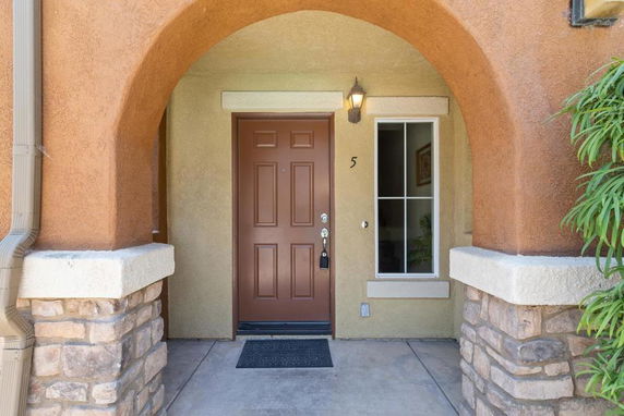 Front view of a house entrance with an arched doorway and brown door.