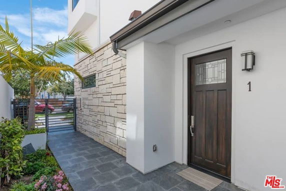 Front entrance of a modern house with a wooden door and stone facade.