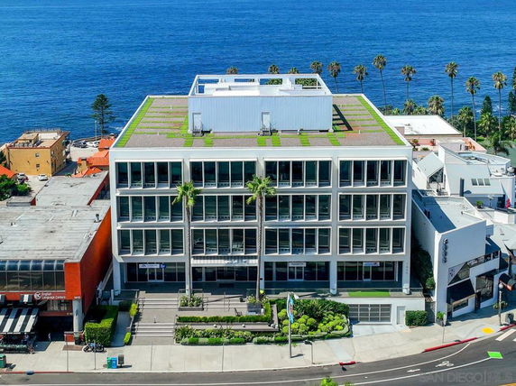 Front view of a multi-story building with a modern design and rooftop greenery.