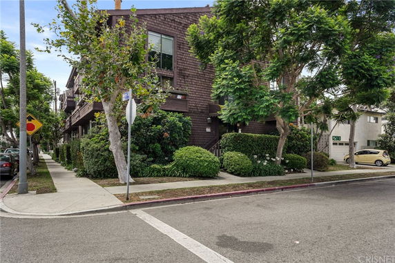Front view of a multi-story residential building with balconies and trees.