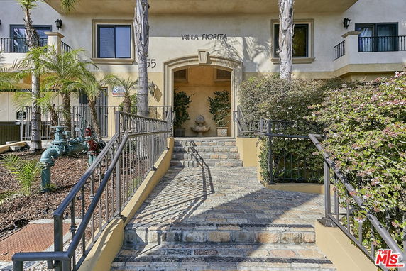Front view of a multi-story building with stairs leading to the entrance.