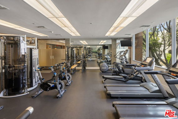 Indoor gym area with exercise equipment and large windows.
