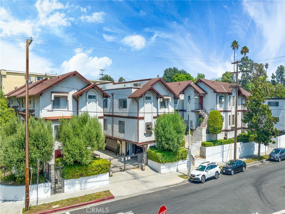 Front view of a multi-story residential building with red gabled roofs and white exterior walls.
