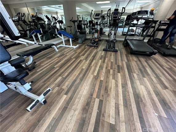 Room with gym equipment including treadmills and exercise machines on a wooden floor.