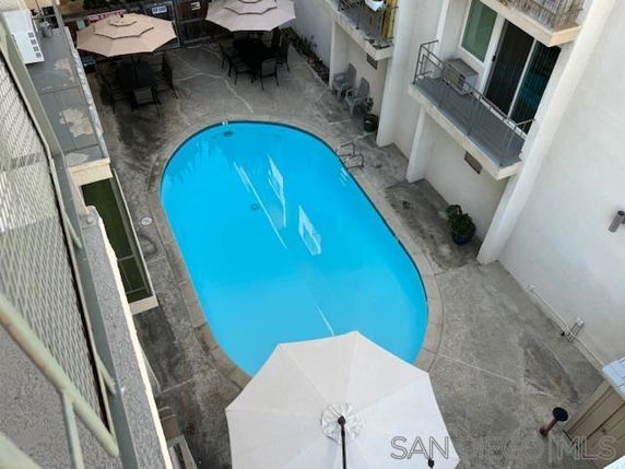 Aerial view of an oval-shaped swimming pool in an outdoor area surrounded by a building.