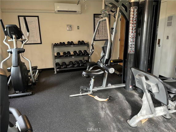 Indoor gym area with exercise equipment including dumbbells, elliptical, and weight machine.