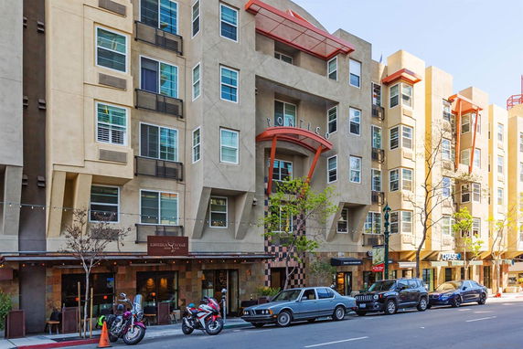Front view of a multi-story apartment building with retail shops on the ground floor.