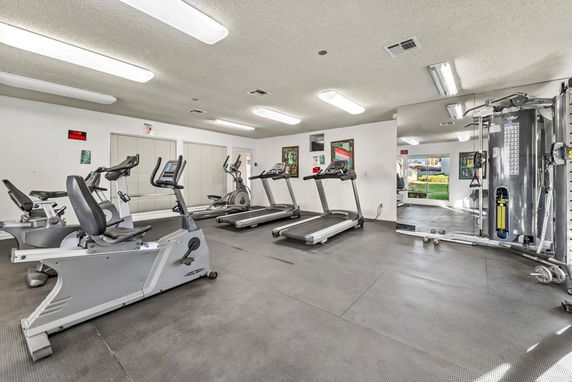 Indoor gym area with exercise equipment including treadmills and stationary bikes.