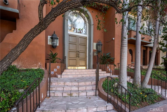 Front view of a building entrance with steps leading up to a large double door and arched window above.