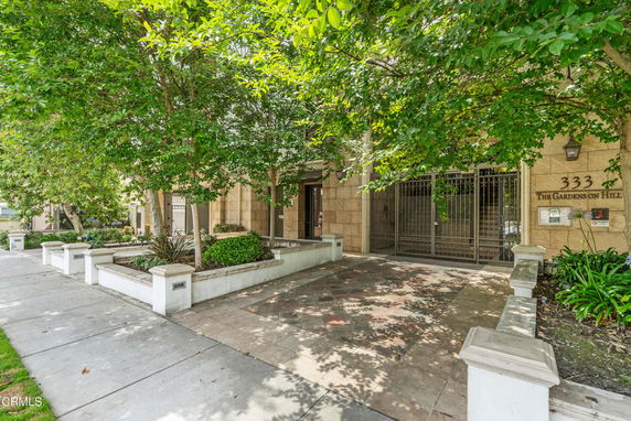 Front view of a building with gated entrance and surrounding greenery.