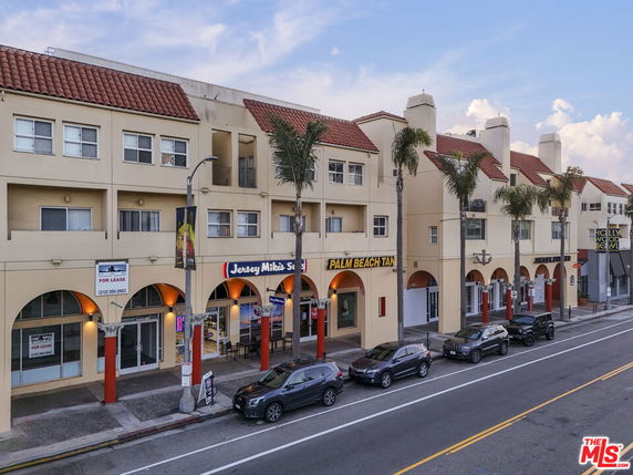 Front view of a multi-story building with retail spaces on the ground floor and residential units above.