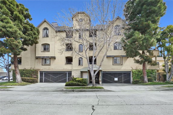 Front view of a multi-story residential building with beige facade and multiple windows.