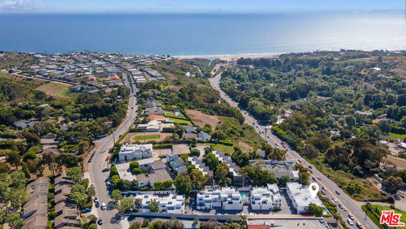 Panoramic aerial view of a coastal area with buildings and roads leading to the ocean.