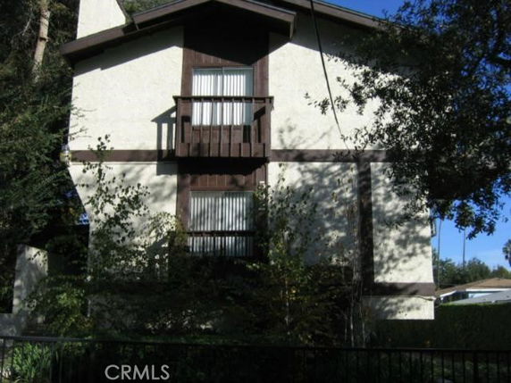 Front view of a two-story house with a small balcony and dark wooden trim.