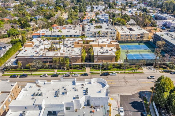 Aerial view of buildings with flat rooftops featuring various installations and adjacent tennis courts.