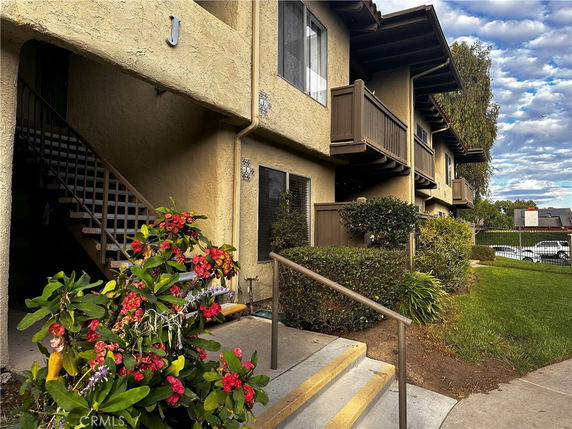 Front view of a two-story residential building with balconies and a staircase.