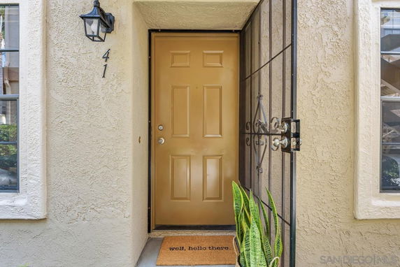 Front view of a house entrance with a tan door and a welcoming doormat.