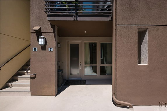 Front view of a multi-story building entrance with numbered units and exterior staircase.