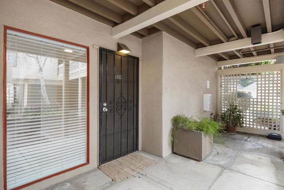 Front view of an apartment entrance with a metal security door and adjacent window with blinds.