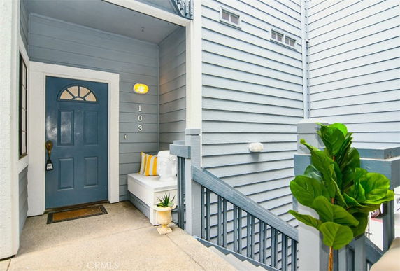 Front view of a house entrance with a blue front door and stairs leading up.