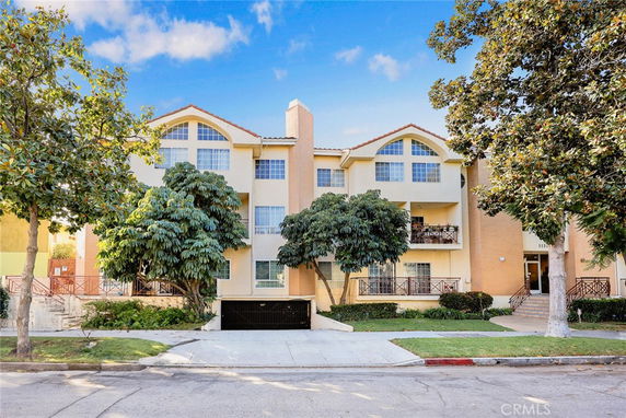 Front view of a multi-story residential building with large windows and a central entrance.