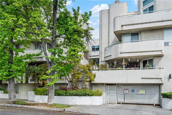 Front view of a multi-story building with balconies and gated entrance.