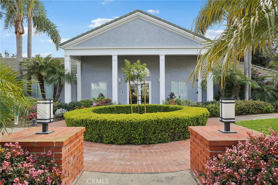 Front view of a house with columns and a landscaped entrance.