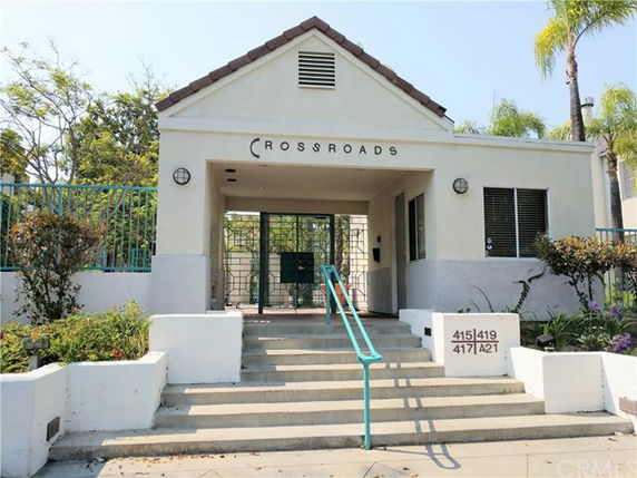 Front view of a building entrance with stairs leading up to a gated entry area and a sign above labeled 'CROSSROADS.'
