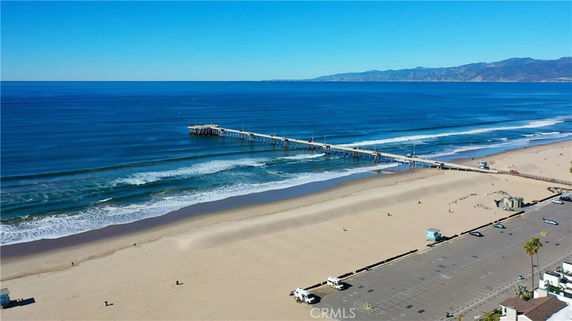 Panoramic view of a beach with a long pier extending into the ocean.