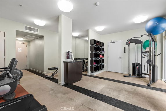 Interior view of a fitness room with exercise equipment and storage shelves.