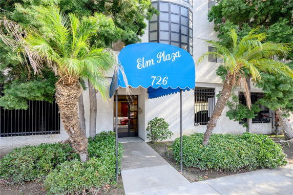 Front view of a building entrance with a blue canopy labeled 'Elm Plaza 726'.
