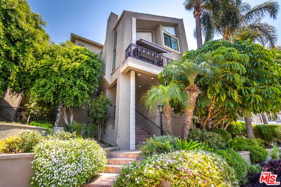 Front view of a multi-story house with a staircase leading to the entrance.
