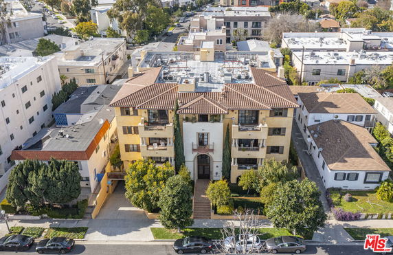 Front view of a multi-story apartment building with a tiled roof and balconies.