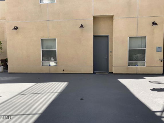 Front view of a building with a flat exterior and two windows flanking a door.