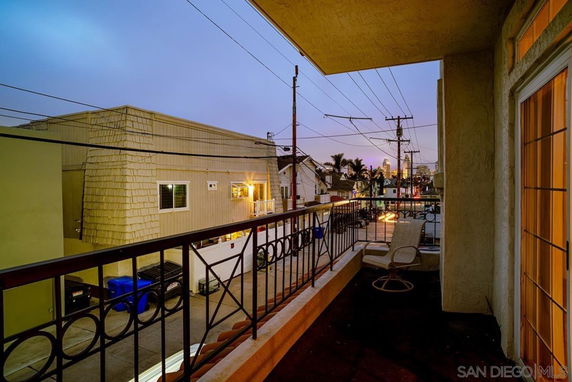 View from a balcony overlooking neighboring structures and city skyline in the distance.