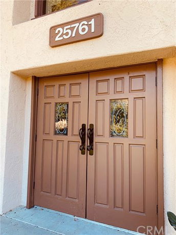 Entrance view of a building with a double door and address number 25761 above it.