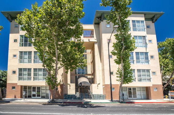 Front view of a multi-story building with large windows and entrance staircase.