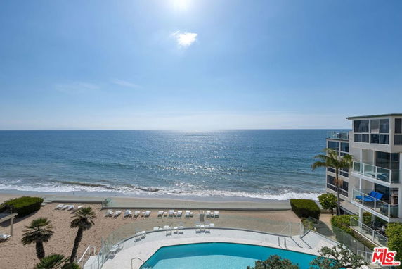 Panoramic view of a beachfront area with a swimming pool and ocean.