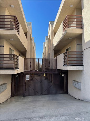 Front view of a multi-story apartment building with balconies and a gated entrance.