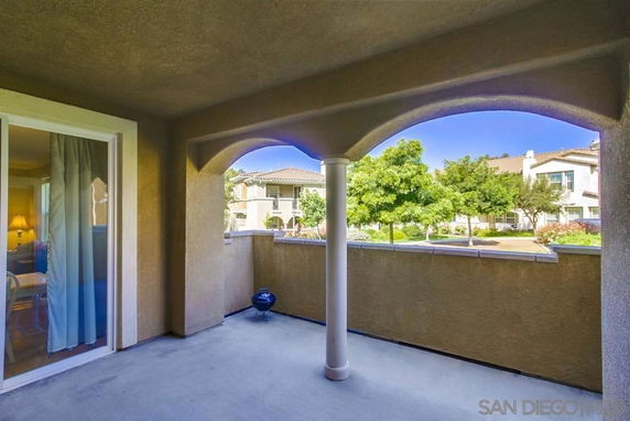 Covered outdoor area with arches and a view of surrounding residential buildings.