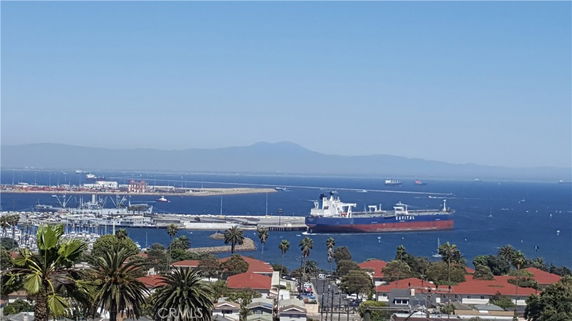 Panoramic view of a coastal area with a large ship in the water and a distant mountain range.